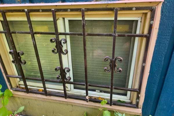 Petite fenêtre en sous-sol avec grille simple à volutes.