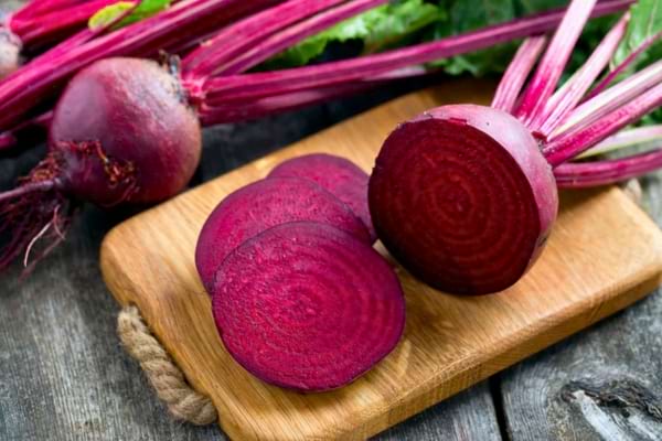 Betteraves rouges tranchées sur planche en bois.