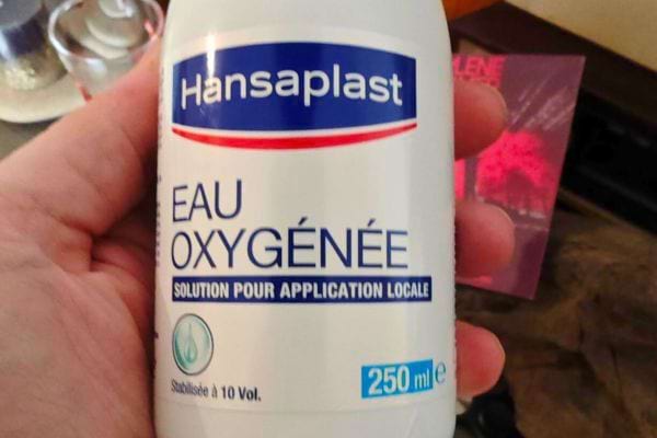 Flacon d’eau oxygénée Hansaplast tenu en main.