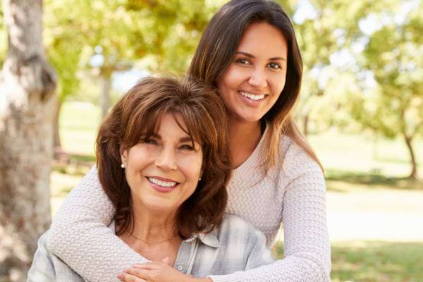 Fille enlace sa mère dans un parc, ambiance joyeuse.