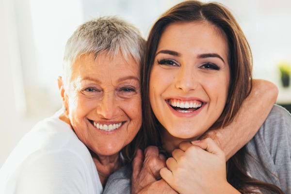 Femme âgée étreint sa fille qui rit aux éclats.
