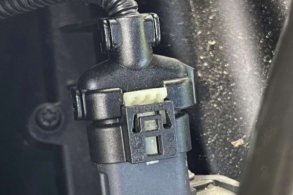 Gros plan sur un capteur moteur noir en bon état.