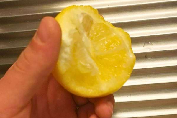 Un demi-citron pressé tenu à la main.