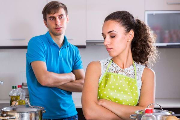 Couple en froid, bras croisés, dans la cuisine.