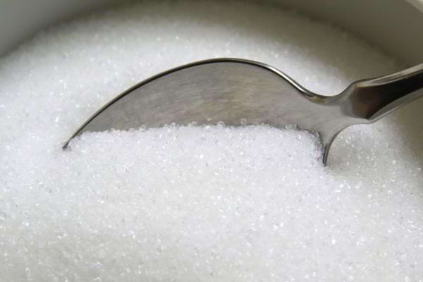 Cuillère en métal plongée dans du sucre blanc cristallisé.