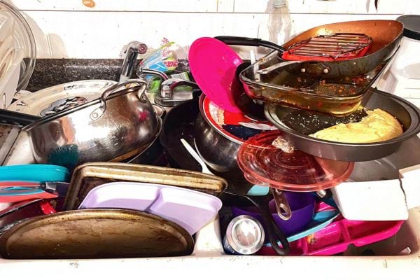 &Eacute;vier d&eacute;bordant de vaisselle grasse et ustensiles entass&eacute;s.