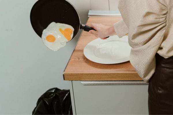 Personne tenant une poêle avec deux œufs cuits.