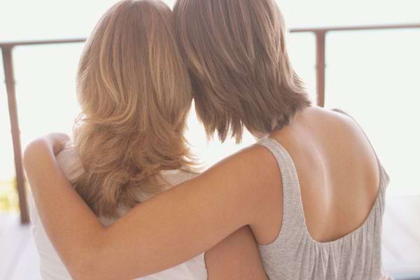 Deux femmes assises, de dos, enlacées en silence.