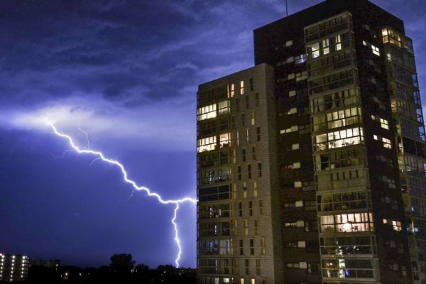 Éclair puissant frappant près d’un immeuble résidentiel.