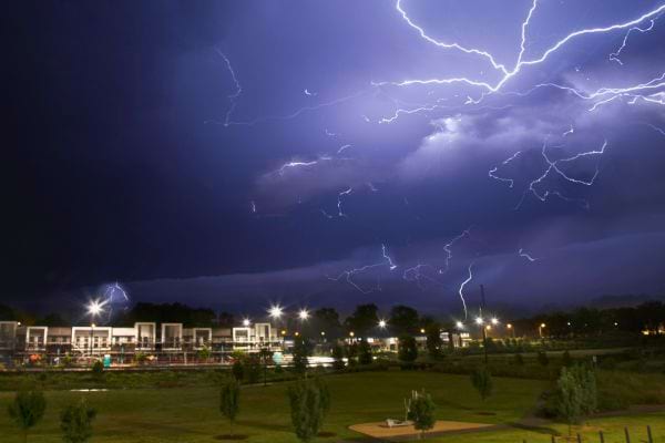 Ciel nocturne zébré d’éclairs au-dessus d’un quartier.