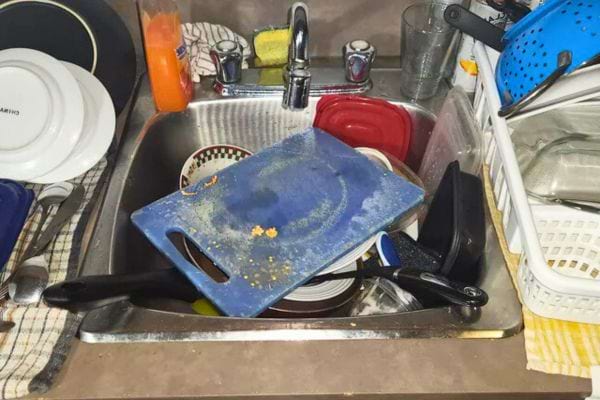 Planche &agrave; d&eacute;couper sale pos&eacute;e sur un &eacute;vier d&eacute;sorganis&eacute;.