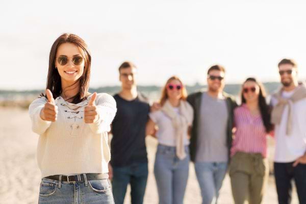 Femme confiante fait des pouces levés devant un groupe.