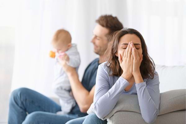 Femme épuisée, homme s’occupe du bébé.