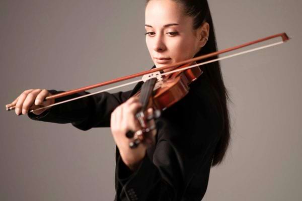 Femme joue du violon avec concentration.