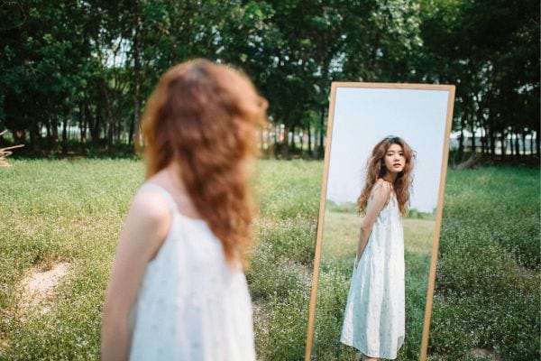 Femme se regarde dans un miroir en plein air.