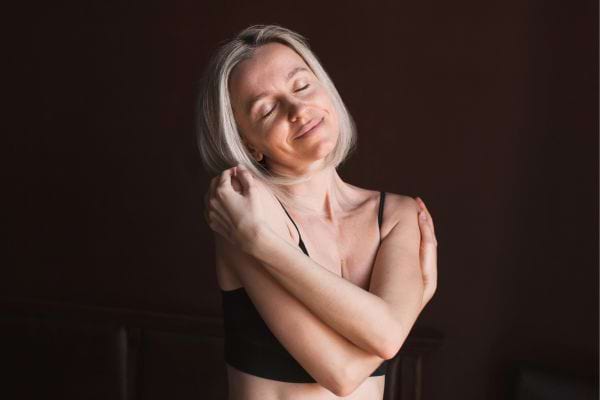 Femme souriante qui se serre dans ses bras.