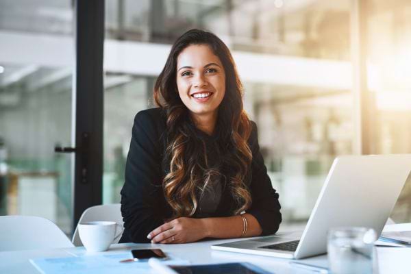 Femme souriante au bureau avec un ordinateur.