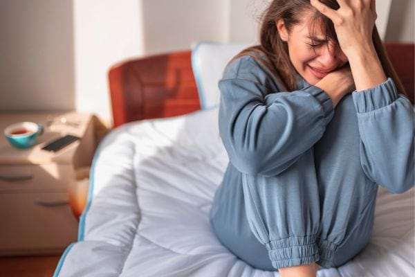 Femme en pleurs sur un lit.