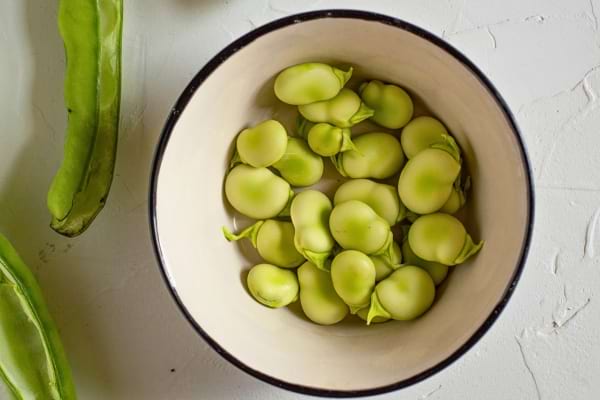Fèves vertes fraîches dans un bol blanc.