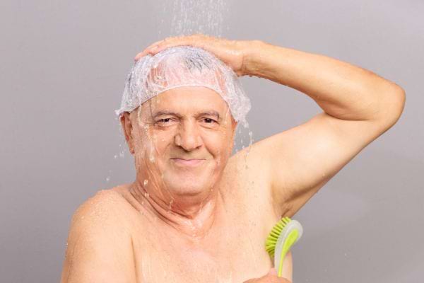 Homme âgé sous la douche avec un bonnet de bain