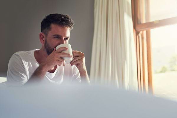 Un homme boit son café seul, pensif.