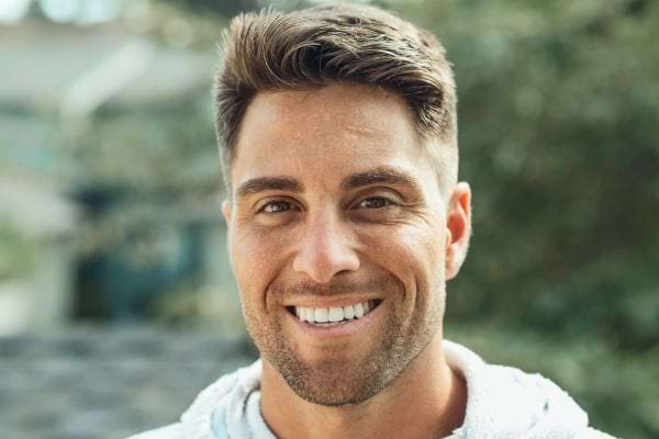 Homme souriant seul en extérieur.