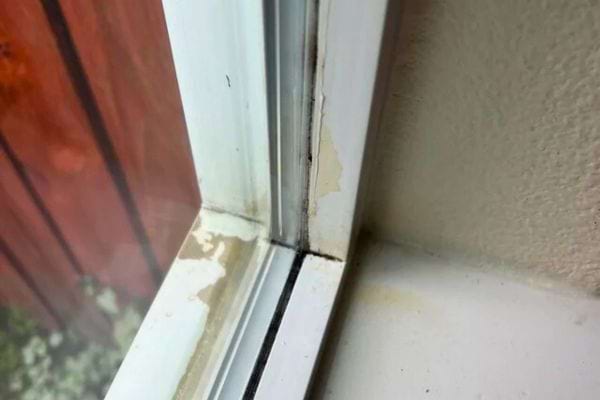 Traces noires et peinture abîmée sur fenêtre.