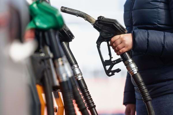 Une personne tient un pistolet de carburant à la pompe.