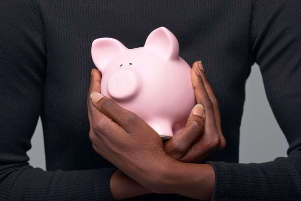 Mains serrent une tirelire rose.