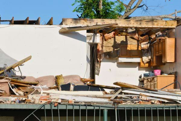 Maison partiellement détruite, toit éventré, intérieur exposé.