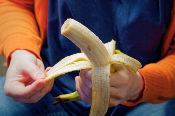 Personne épluche une banane à deux mains.