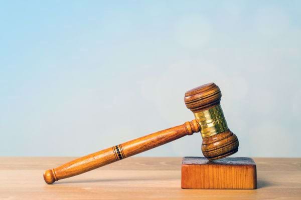 Marteau de juge posé sur un bureau en bois.