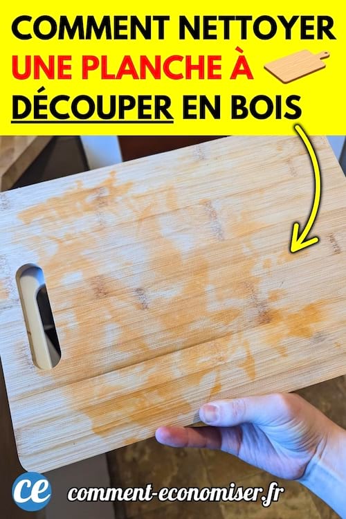 Main tenant une planche à découper en bois tachée, au-dessus d’un évier de cuisine.
