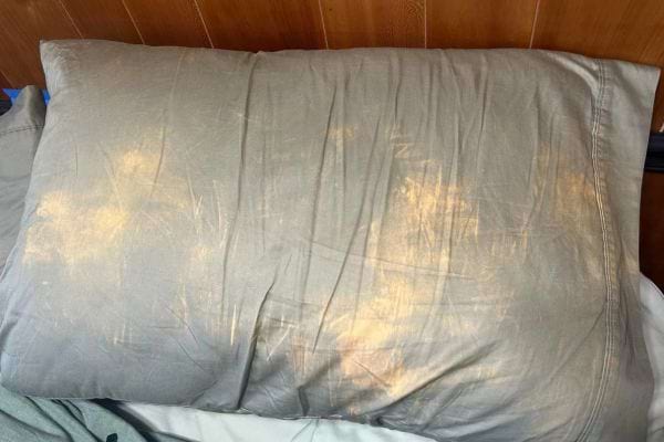 Un oreiller présente de nombreuses taches jaunes visibles.