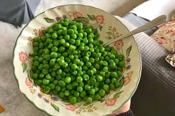 Petits pois verts servis dans une assiette fleurie.