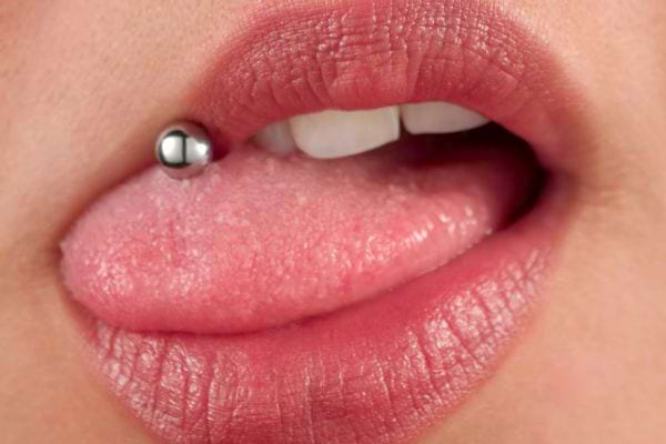 Langue sortie avec piercing boule argentée et lèvres entrouvertes.