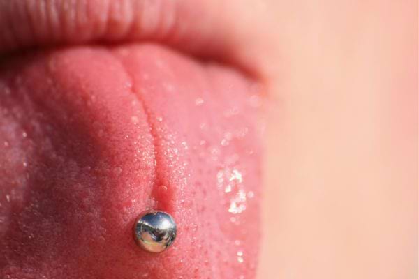 Gros plan sur une langue percée avec bijou métallique brillant.