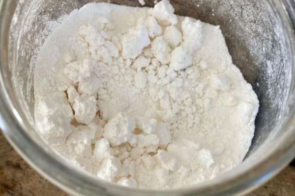 Gros plan sur une poudre blanche granuleuse dans un bocal.