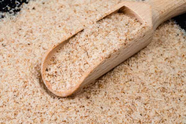 Du psyllium en poudre avec une cuillère en bois.