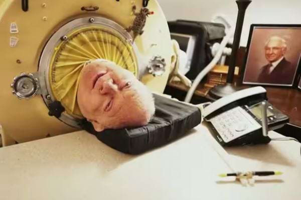 Homme allongé dans son poumon en acier, téléphone et photo à côté.