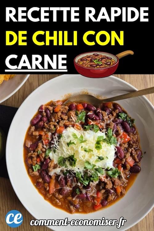 Assiette de chili con carne maison garnie de fromage râpé et de coriandre fraîche, accompagnée d'une cuillère en bois.