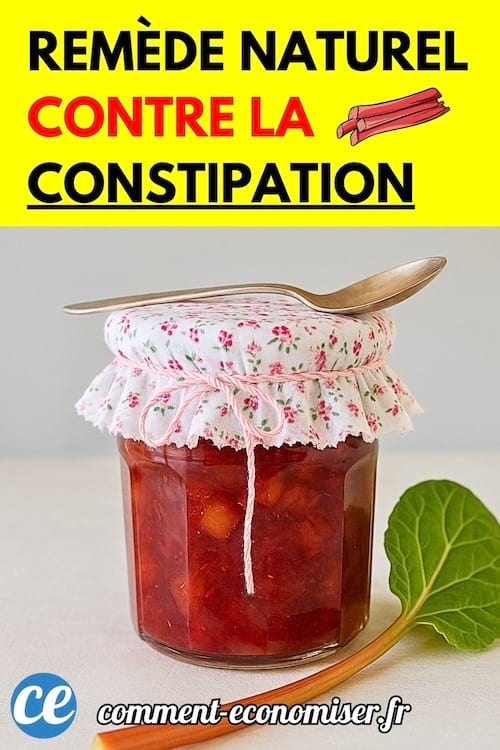 Pot de confiture de rhubarbe maison recouvert d’un tissu fleuri et accompagné d’une cuillère et d’une feuille verte.