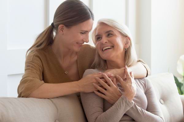 Regard tendre et câlin entre mère et fille sur canapé.