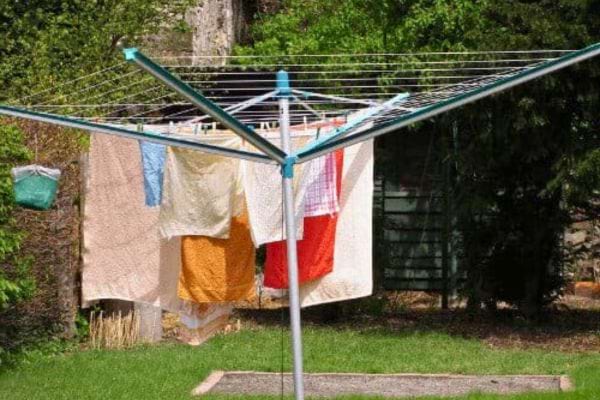 Étendoir rotatif plein de linge coloré dans un jardin.