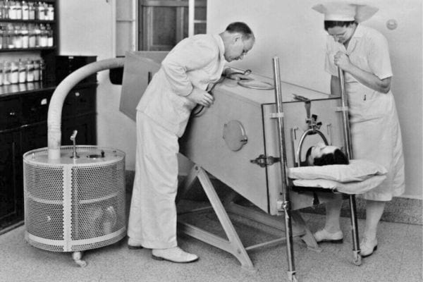 Médecin et infirmière surveillent un patient dans un ancien appareil.