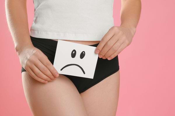Femme en sous-vêtement tenant un dessin triste sur le bas-ventre.