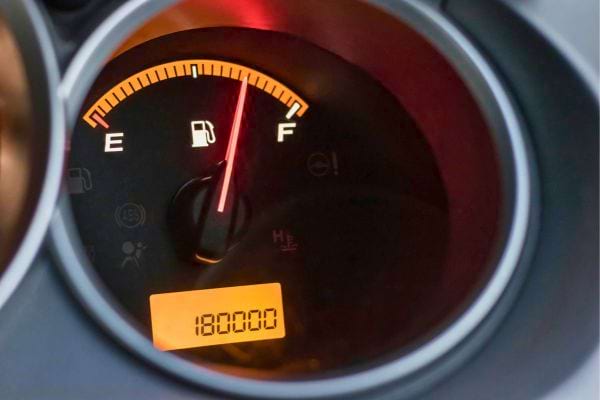 Compteur de voiture affichant 180000 km et réservoir plein.