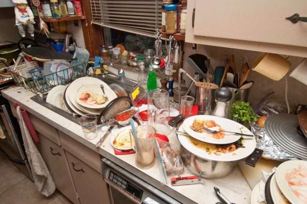 &Eacute;vier rempli d&rsquo;assiettes sales, bols et casseroles empil&eacute;s.