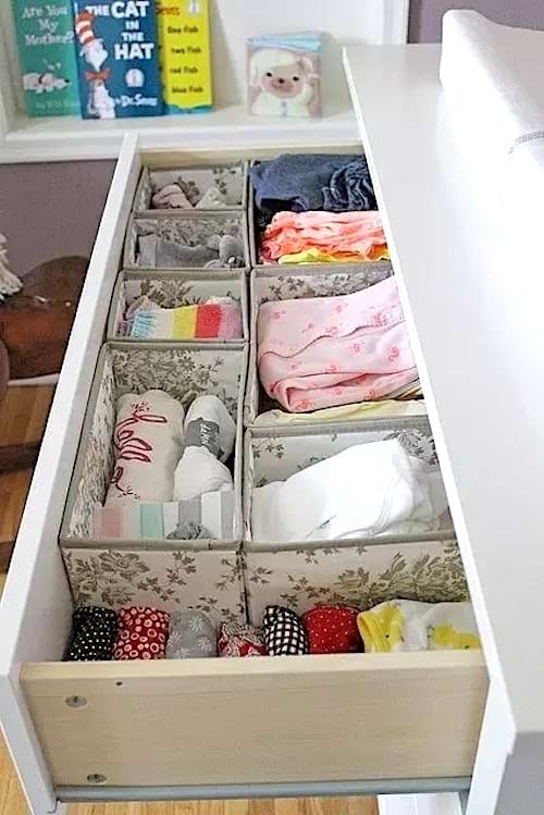 Un tiroir de commode blanc avec des affaires de bébé dedans
