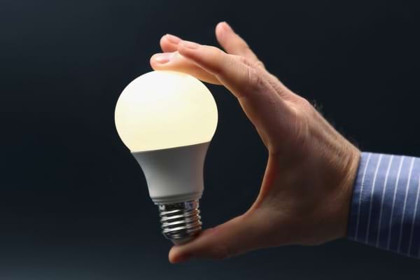 Main tenant une ampoule LED allumée.